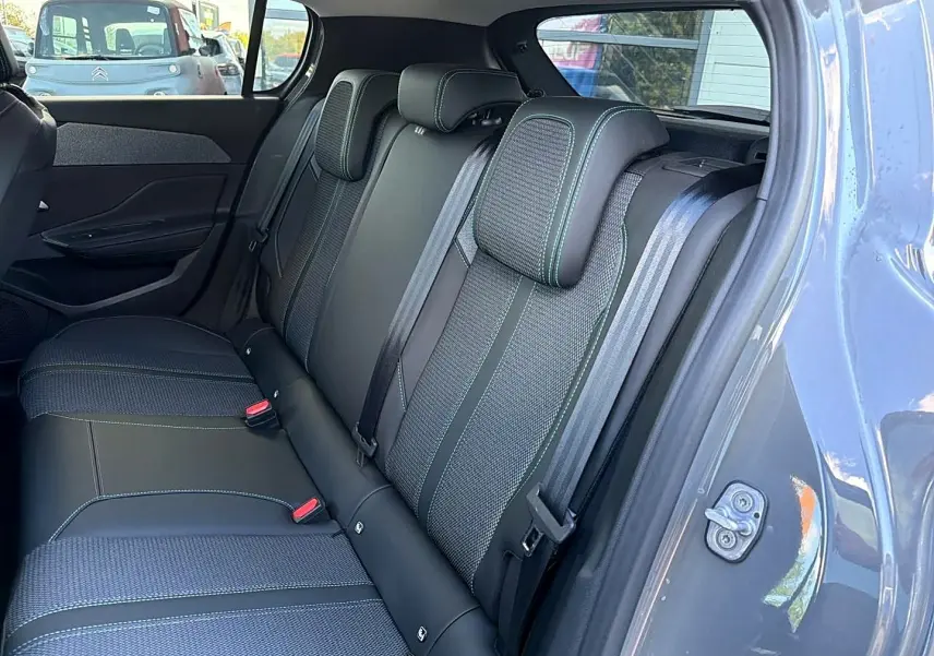 Vue intérieure côté droit sur la banquette arrière en tissu et cuir noir avec surpiqûres vertes d'une Peugeot 308 gris selenium.