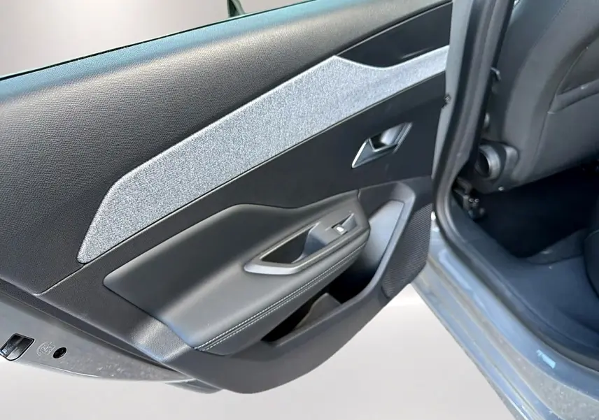 Gros plan sur la porte arrière gauche gris selenium d’une Peugeot 308 2025 avec habillage tissu clair et commandes de vitre.