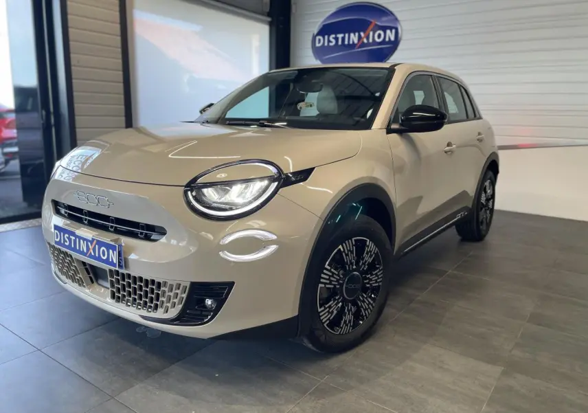 Vue 3/4 avant droit d'une FIAT 600 beige métallisé avec jantes alliage noires et détails chromés showroom.