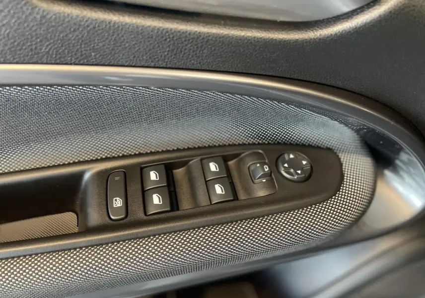 Gros plan sur les commandes de lève-vitres et rétroviseurs côté gauche de la FIAT 600 beige métallisé 2025.