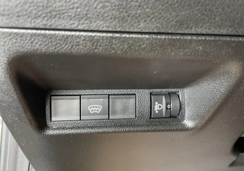 Gros plan sur les commandes de réglage des phares et dégivrage, intérieur noir de la Fiat 600 beige métallisé.