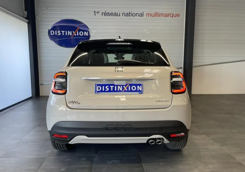 Vue arrière d'une FIAT 600 beige métallisé avec double sortie d'échappement côté droit et feux arrière LED allumés.