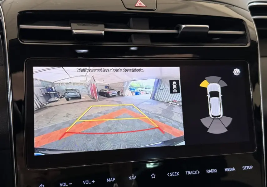 Écran tactile du Hyundai Tucson noir montrant la caméra de recul et l'aide au stationnement arrière.