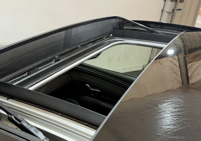 Toit ouvrant panoramique ouvert sur un Hyundai Tucson noir, vue rapprochée du toit et intérieur côté passager.
