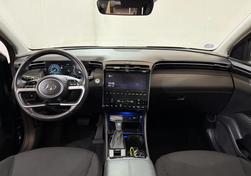 Vue intérieure avant du Hyundai Tucson noir 2021, tableau de bord moderne avec écran tactile central et volant multifonction.
