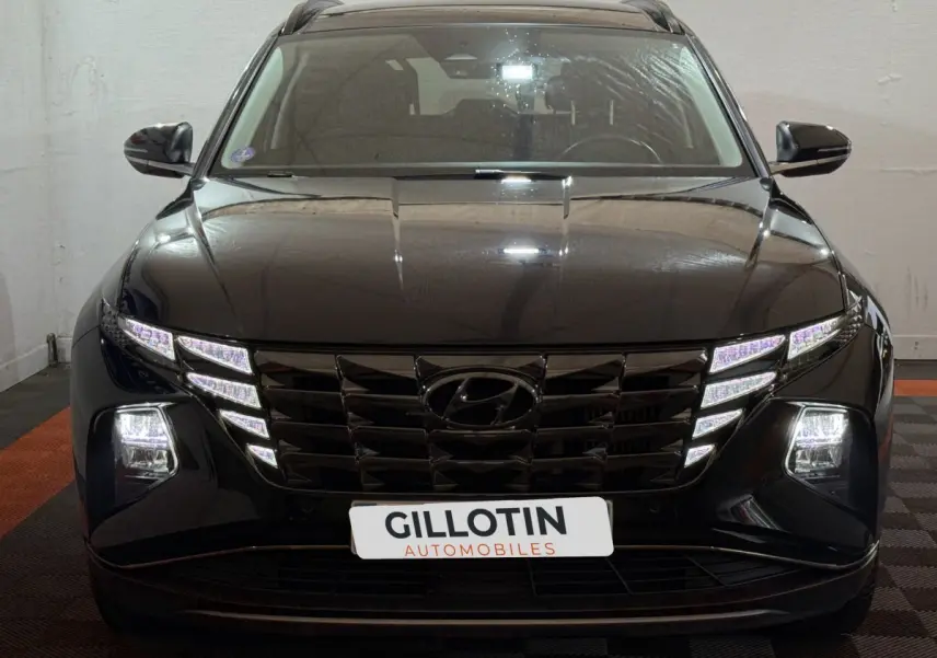 Vue frontale d'un Hyundai Tucson noir 2021 avec phares LED et calandre distinctive allumée.