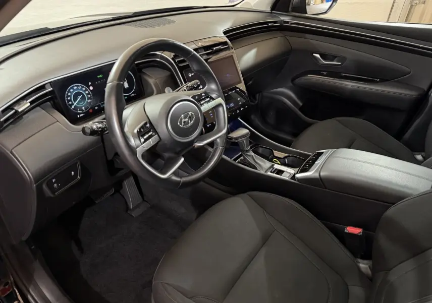 Intérieur noir du Hyundai Tucson 2021, vue côté conducteur sur le tableau de bord et la console centrale moderne.
