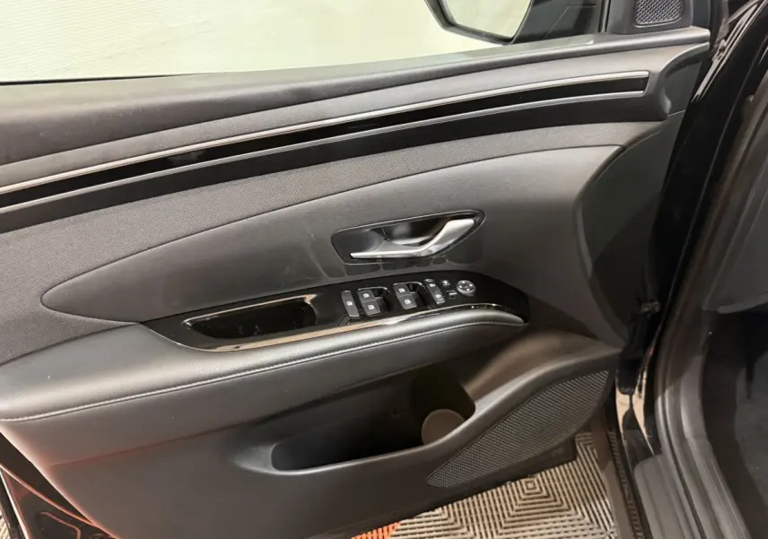 Gros plan sur la porte avant gauche noire du Hyundai Tucson 2021, avec commandes électriques et poignée argentée.