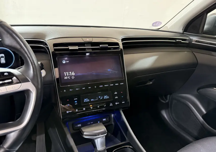 Vue intérieure côté conducteur du tableau de bord noir du Hyundai Tucson 2021 avec écran tactile et levier de vitesse automatique.