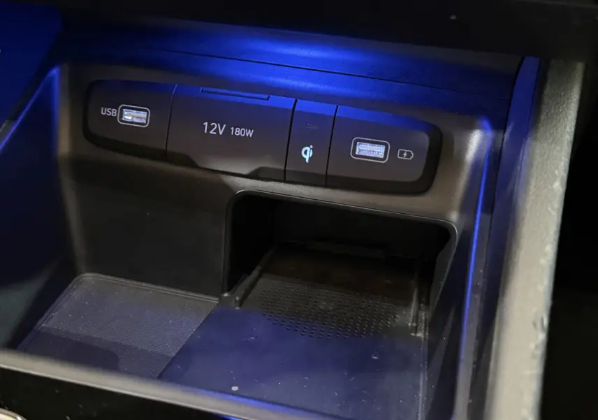 Gros plan sur la console centrale noire du Hyundai Tucson 2021, montrant ports USB, prise 12V et chargeur à induction.