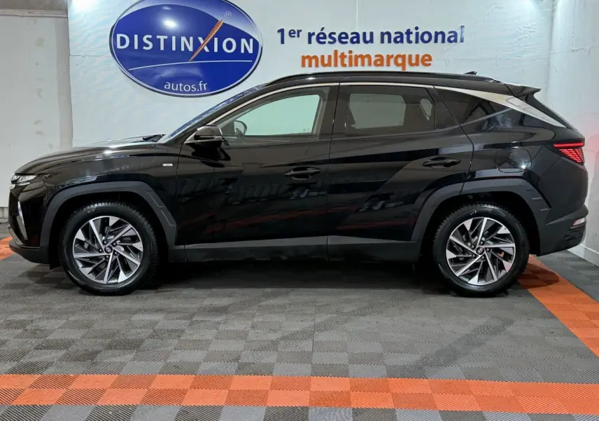 Profil côté gauche d'un Hyundai Tucson noir 2021 garé en intérieur avec jantes alliage et vitres teintées.
