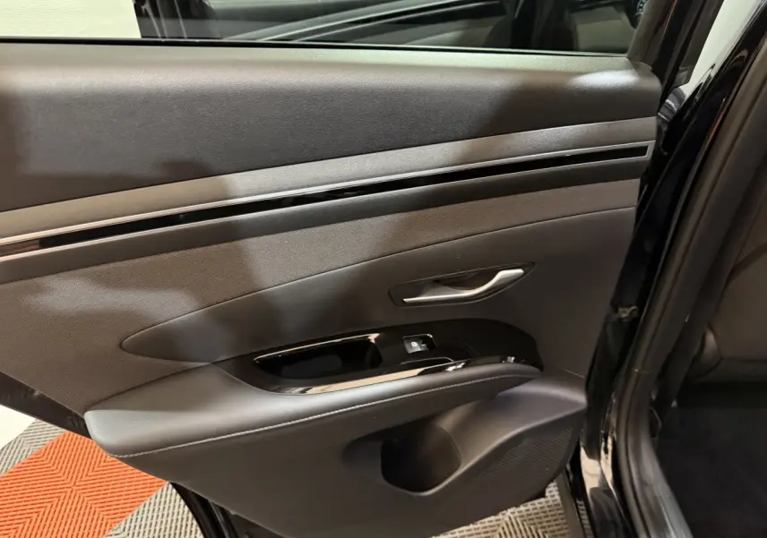 Vue côté gauche de la porte arrière noire du Hyundai Tucson 2021 avec poignée argentée et commande de vitre.