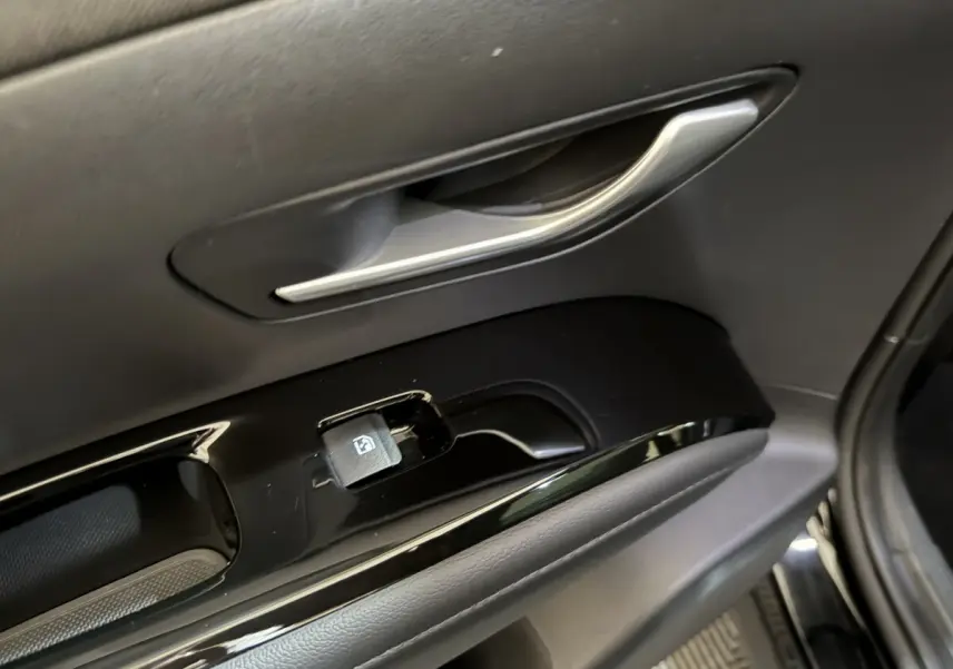 Poignée intérieure et commandes de lève-vitre côté conducteur du Hyundai Tucson noir, vue rapprochée du panneau de porte.