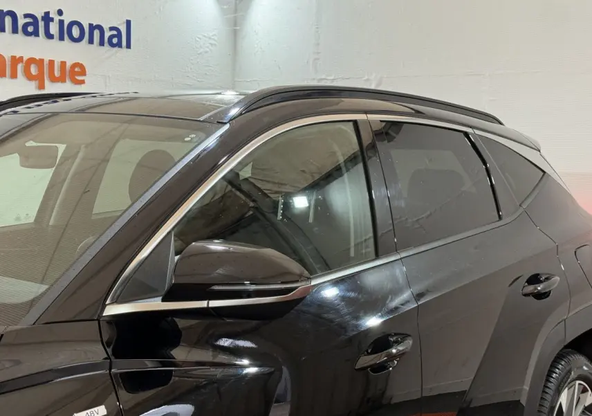 Vue latérale côté gauche d'un Hyundai Tucson noir 2021 avec rétroviseur et vitres teintées visibles.