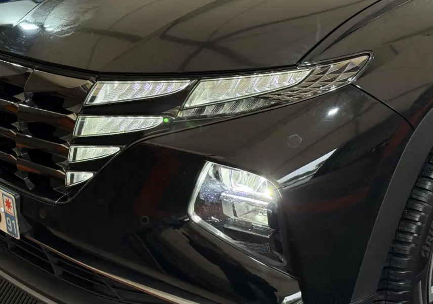 Gros plan sur l'avant droit noir du Hyundai Tucson 2021, mettant en valeur ses phares LED et sa calandre distinctive.