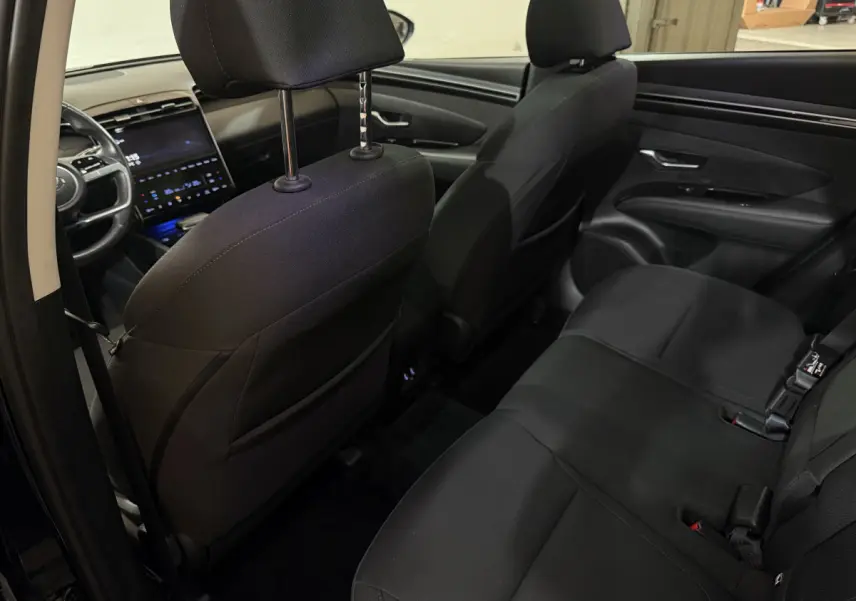Vue intérieure arrière côté gauche du Hyundai Tucson 2021 noir, montrant les sièges arrière et le tableau de bord avant.