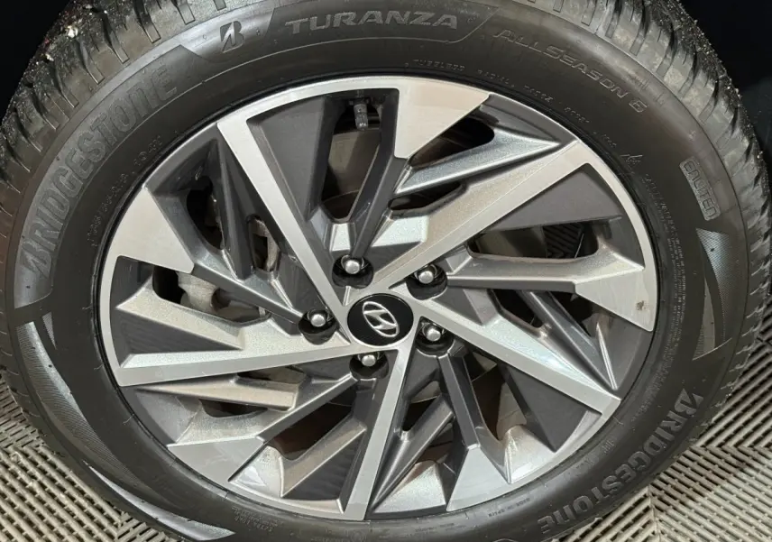 Gros plan sur la jante alliage argentée du Hyundai Tucson noir, pneu Bridgestone Turanza visible autour.