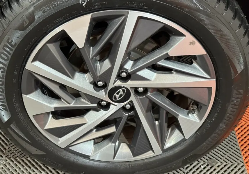 Gros plan sur la jante alliage au design géométrique du Hyundai Tucson noir 2021, roue Bridgestone visible.