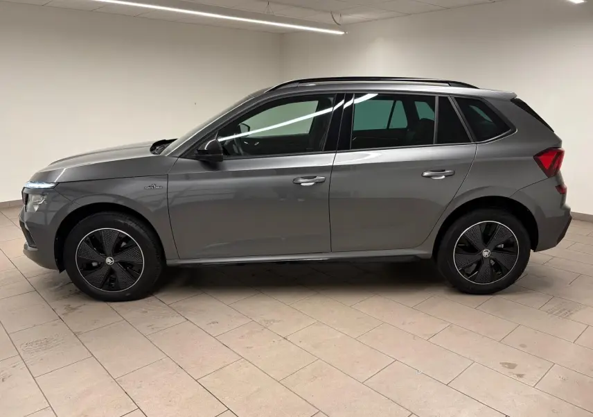 Vue de profil côté gauche d’un Skoda Kamiq 1.5 TSI Monte Carlo gris graphite avec jantes noires distinctives.