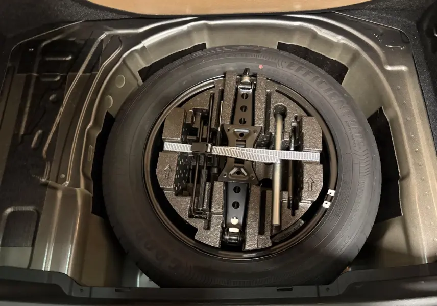 Vue plongeante sur la roue de secours et les outils de bord dans le coffre du Skoda Kamiq 1.5 TSI 150 DSG7 Monte Carlo gris graphite 2024.