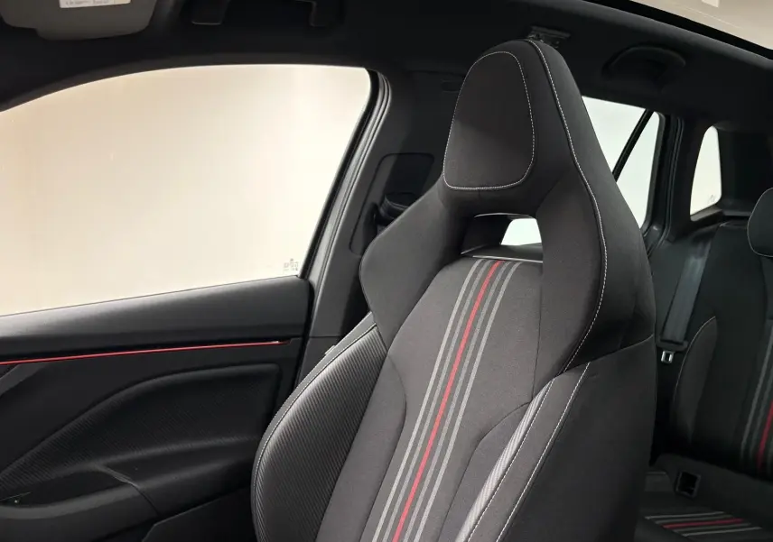 Vue intérieure côté gauche du siège avant sport noir avec surpiqûres blanches et bandes grises et rouges du Skoda Kamiq Monte Carlo 2024.