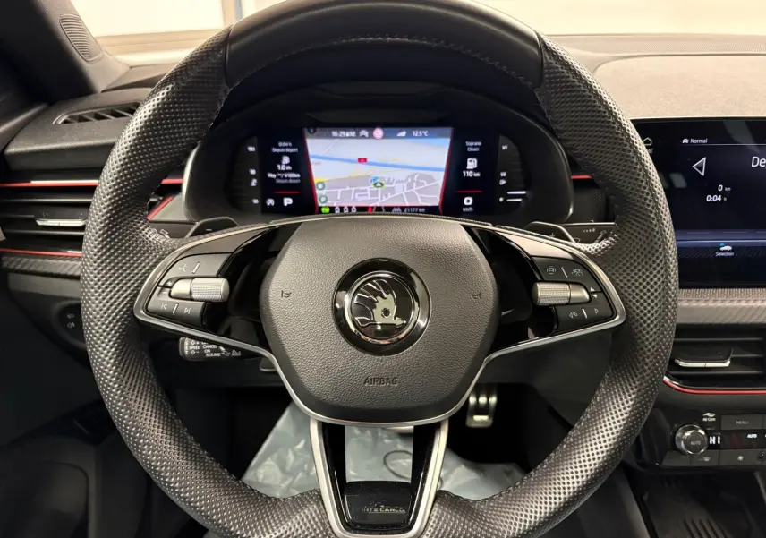 Vue rapprochée du volant perforé du Skoda Kamiq Monte Carlo 2024 avec tableau de bord numérique et détails en gris graphite.