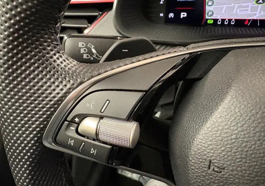 Gros plan sur les commandes gauche du volant perforé du Skoda Kamiq 2024 Monte Carlo, avec molette métallique et tableau de bord numérique.