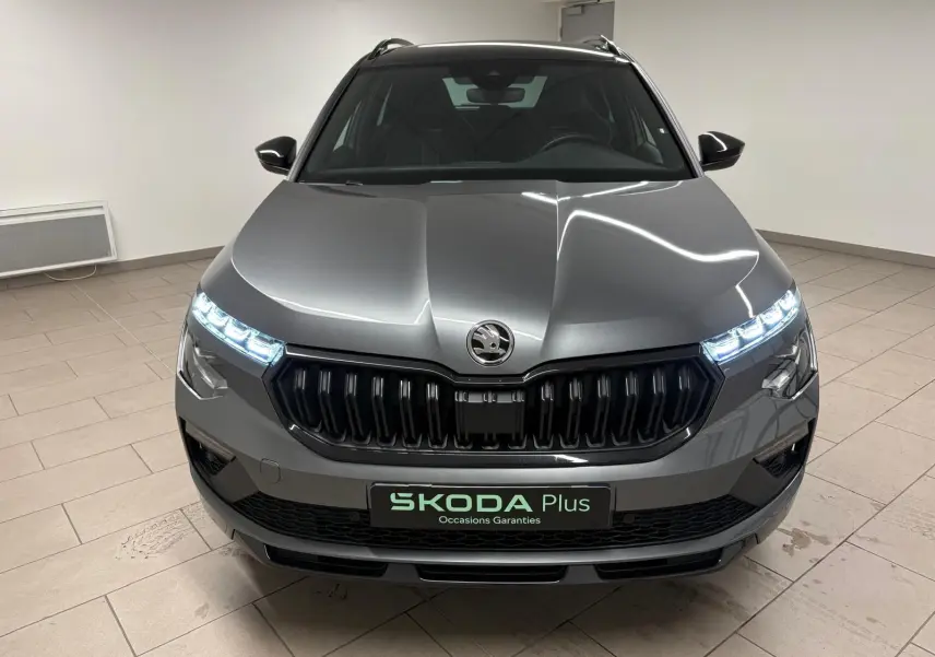 Vue frontale d'un Skoda Kamiq 1.5 TSI 150 DSG7 Monte Carlo gris graphite avec feux LED allumés en intérieur.