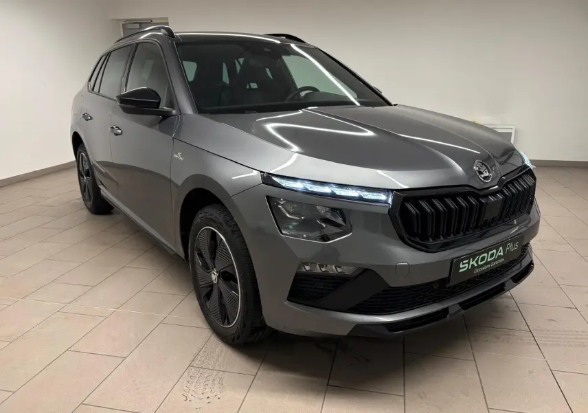 Vue 3/4 avant droite d’un Skoda Kamiq Monte Carlo 2024 gris graphite avec calandre noire et jantes spécifiques.