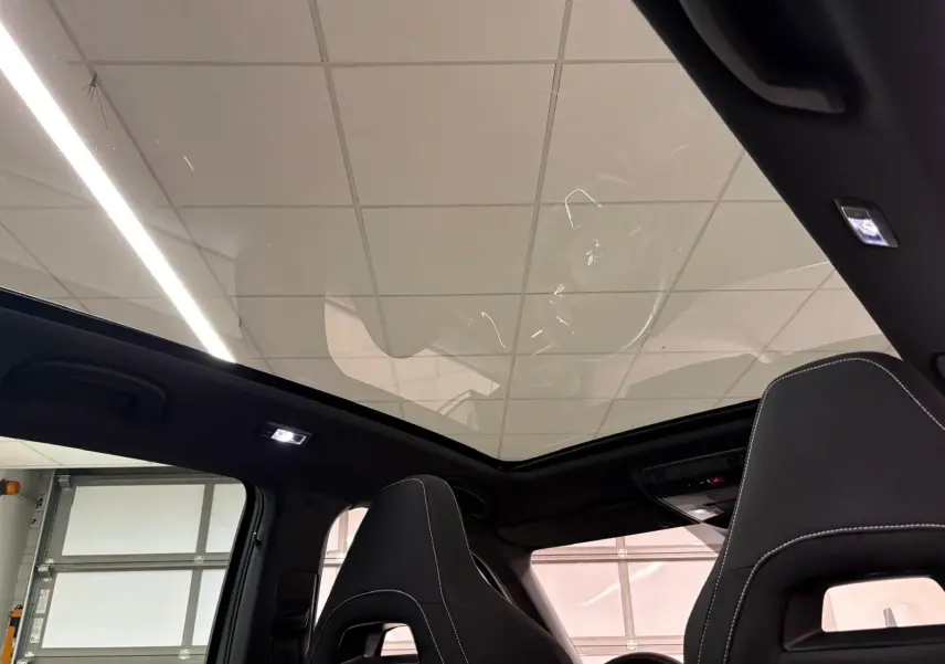 Toit panoramique en verre vu de l'intérieur du Skoda Kamiq Monte Carlo 2024 avec sièges noirs et surpiqûres blanches.