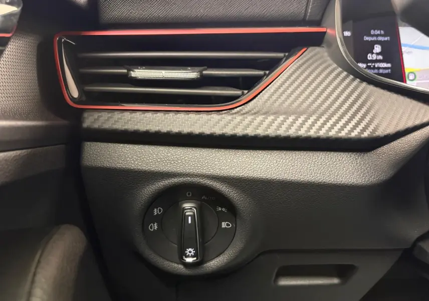 Détail intérieur du tableau de bord du Skoda Kamiq Monte Carlo 2024, avec commande d'éclairage et finition carbone gris graphite.