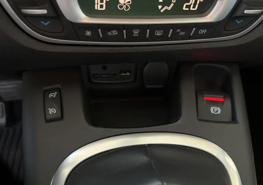 Détail de la console centrale du Renault Scenic gris Cassiopée 2015, avec commandes climatisation et frein à main électrique.