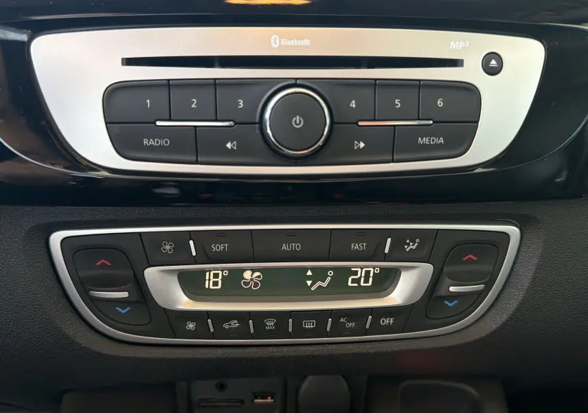 Vue rapprochée du tableau de bord central du Renault Scénic 1.5 DCI 110 Bose, montrant la radio Bluetooth et la climatisation automatique.