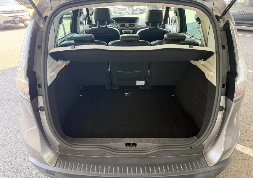 Coffre ouvert vu de l'arrière d'un Renault Scénic gris Cassiopée, montrant l'espace de chargement et l'intérieur noir.