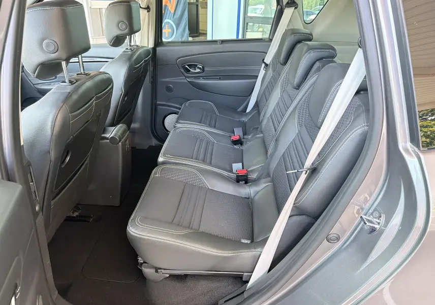 Vue latérale intérieure sur les sièges arrière en cuir noir du Renault Scénic gris Cassiopée, avec ceinture de sécurité attachée.