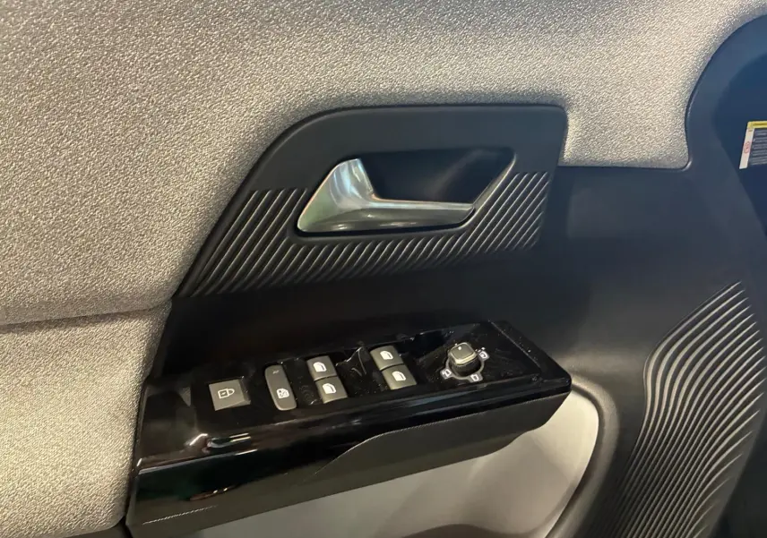 Détail de la porte côté gauche de la Citroën C5 Aircross 1.2 Hybrid 145 BVA Max avec commandes de vitres et poignée argentée.