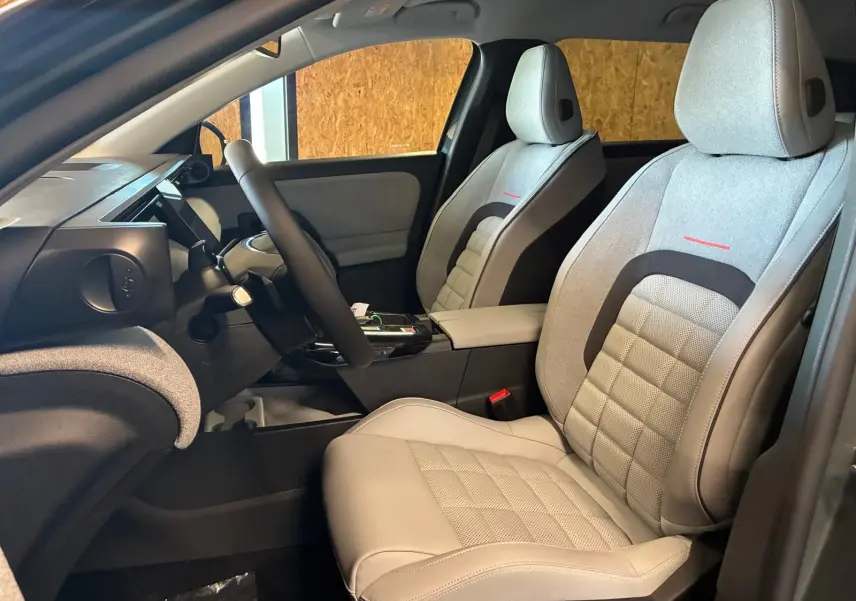 Vue intérieure côté gauche du Citroën C5 Aircross 2026, sièges gris clair avec surpiqûres rouges et volant multifonction.