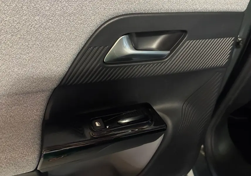 Gros plan sur la poignée intérieure et commande de lève-vitre côté gauche du Citroën C5 Aircross 2026, finition tissu gris noir.
