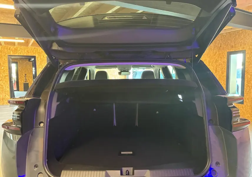 Coffre ouvert vu de l'arrière d'un Citroën C5 Aircross Vert Astoria Metal dans un intérieur en bois.