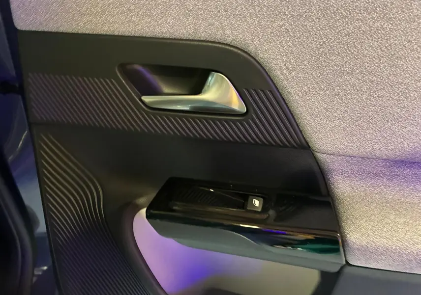 Détail de la porte intérieure côté gauche du Citroën C5 Aircross vert Astoria, avec poignée argentée et commande de fenêtre.