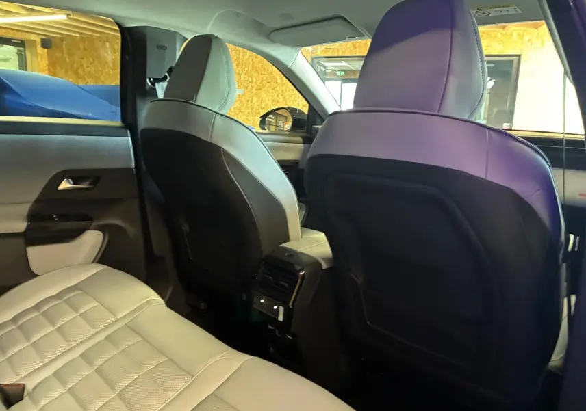 Vue intérieure arrière du Citroën C5 Aircross 2026, sièges en cuir beige clair avec dossier noir et console centrale avec aérateurs.