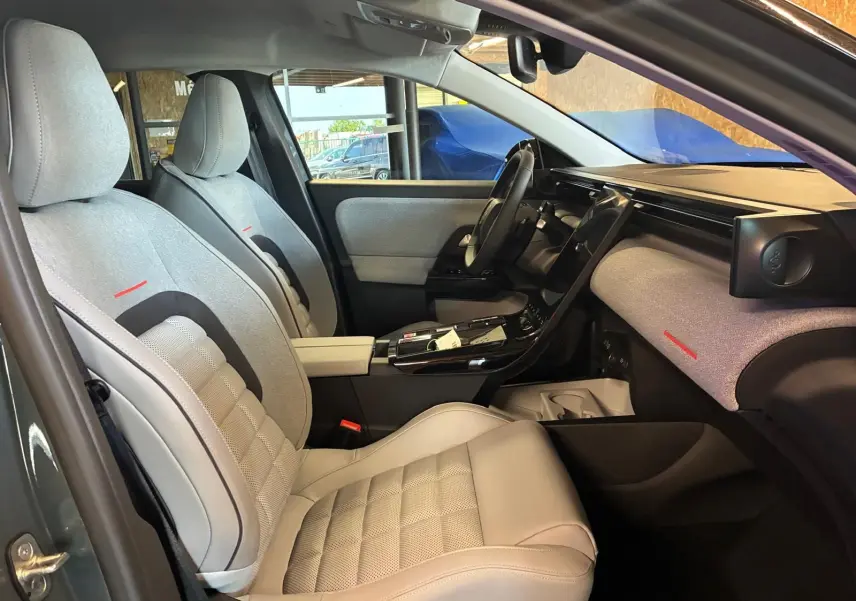Vue intérieure côté conducteur de la Citroën C5 Aircross 2026, sièges gris clair avec détails rouges et tableau de bord épuré.