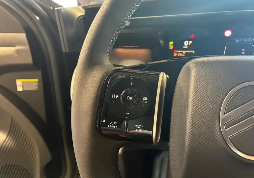 Gros plan sur la commande multifonction gauche du volant en cuir noir du Citroën C5 Aircross 2026, détails des boutons assist et limit.