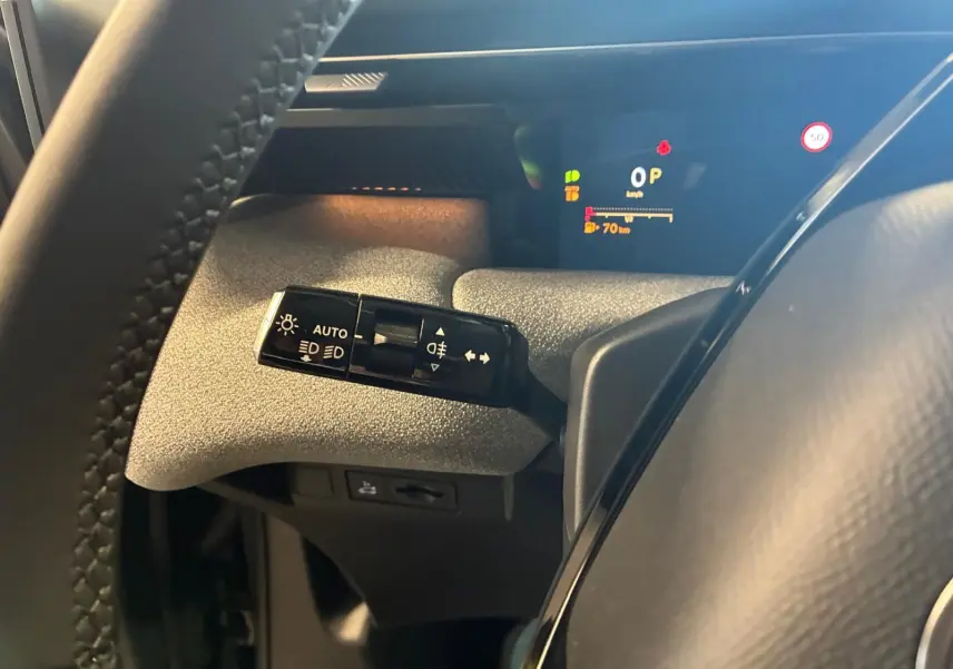 Gros plan sur la commande des feux et clignotants à gauche du volant dans le cockpit du Citroën C5 Aircross vert Astoria.
