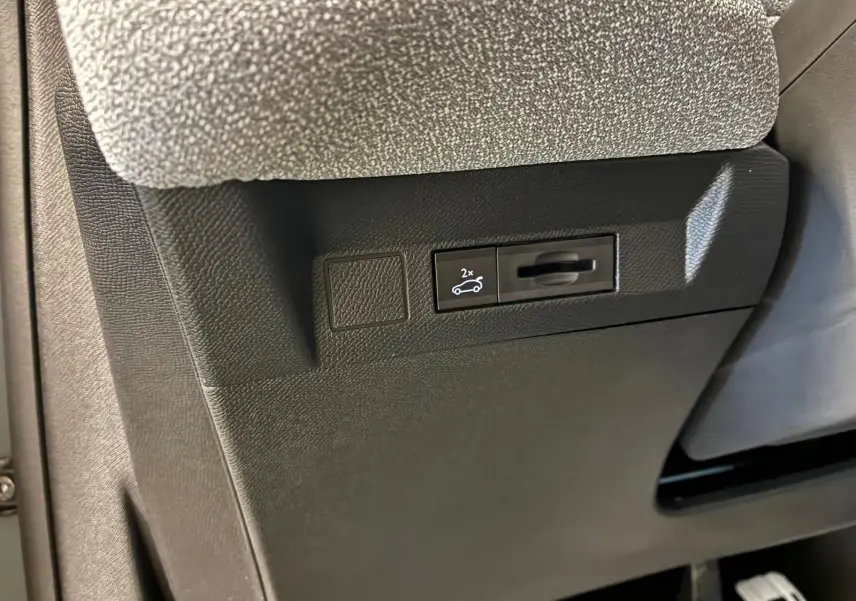 Détail intérieur montrant le bouton d'ouverture électrique du hayon sur la partie inférieure côté conducteur du Citroën C5 Aircross hybride.