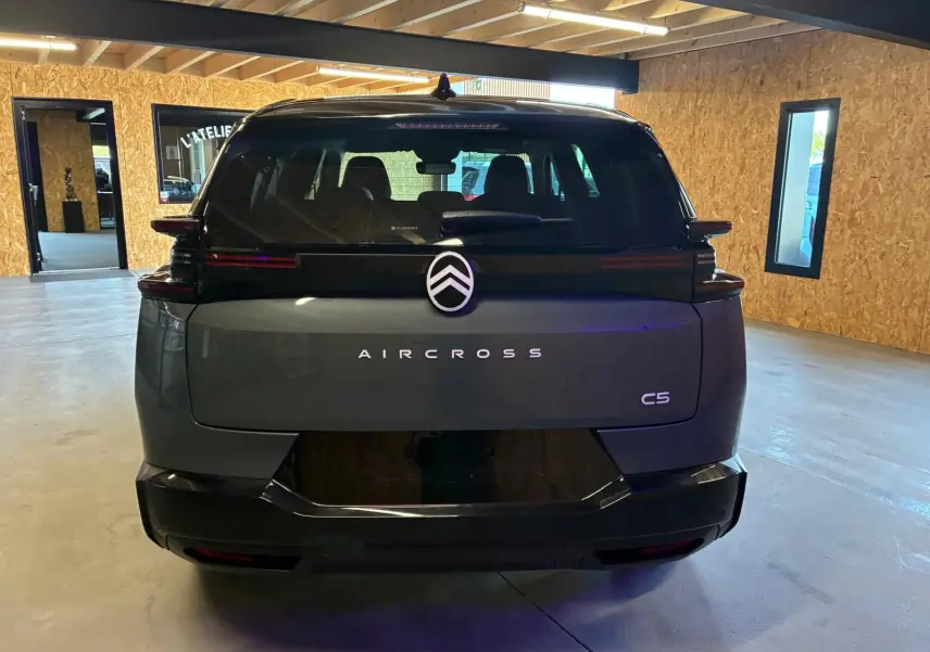 Vue arrière d'un Citroën C5 Aircross 2026 vert Astoria Metal, avec logo et nom du modèle bien visibles dans un intérieur lumineux.