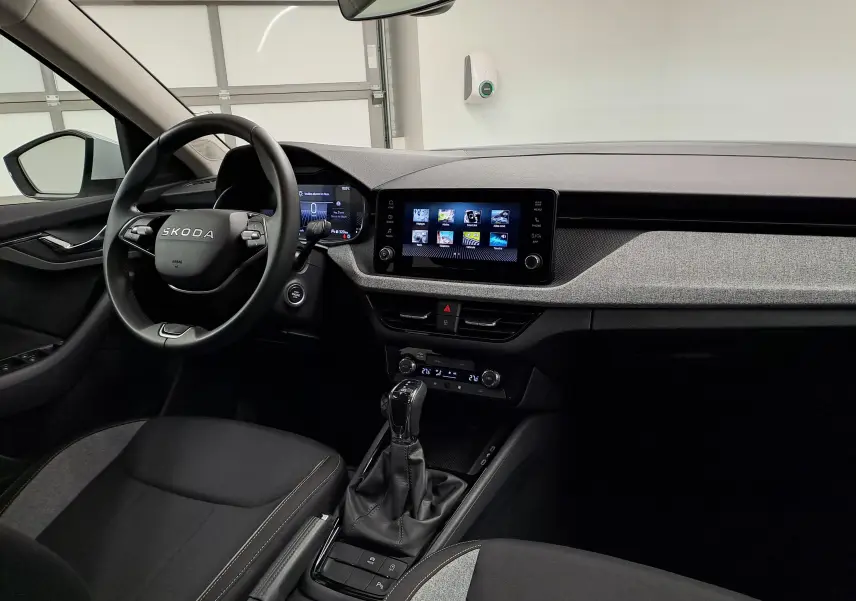 Vue intérieure côté conducteur du Skoda Kamiq 2025, tableau de bord moderne avec écran tactile et volant multifonction noir.