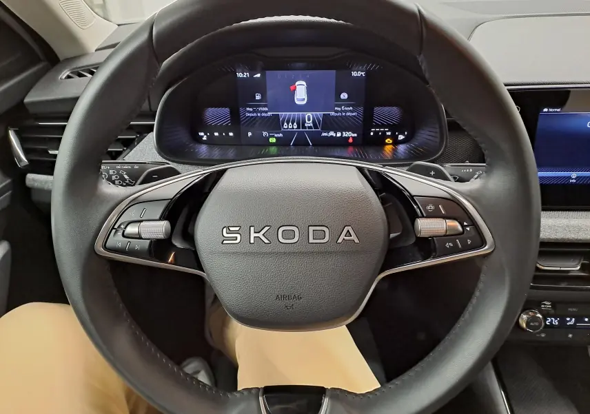 Vue rapprochée du volant SKODA KAMIQ 2025 avec tableau de bord numérique et commandes intégrées, intérieur noir.