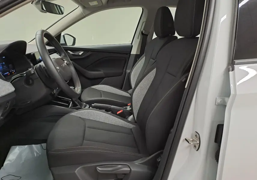 Vue intérieure côté conducteur du Skoda Kamiq blanc Lune 2025, sièges tissu bicolore gris et noir, volant multifonction.
