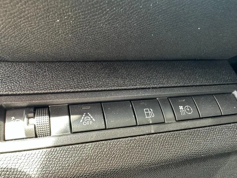 Gros plan sur les boutons de commande noirs du tableau de bord du Peugeot 3008 Hybride Rechargeable 2024.